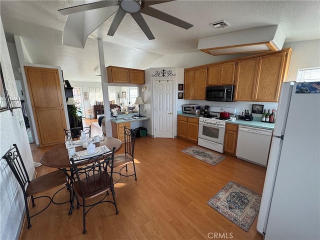 kitchen featuring white appliances, light hardwood / wood-style flooring, a wealth of natural light, a textured ceiling, and vaulted ceiling