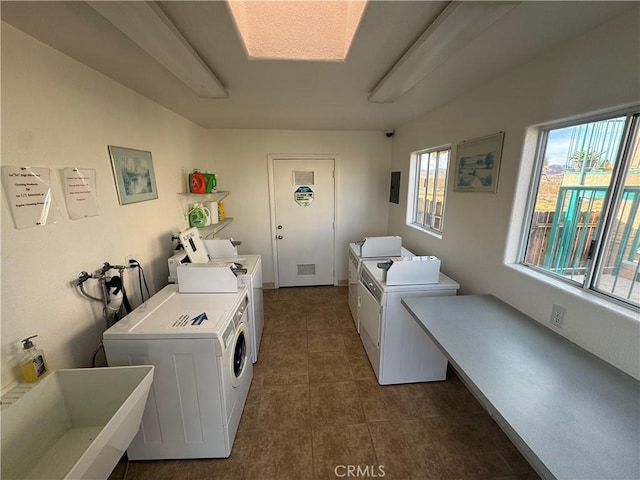 laundry room featuring separate washer and dryer, sink, plenty of natural light, and dark tile patterned floors