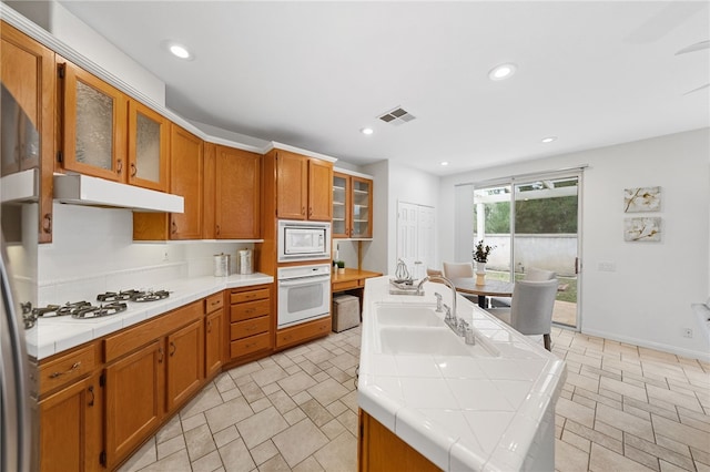 kitchen featuring a kitchen island, sink, tile counters, and white appliances