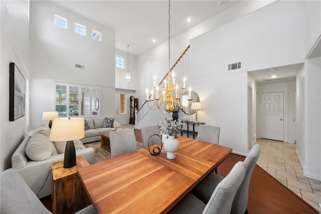 dining room featuring a towering ceiling, light tile patterned floors, and an inviting chandelier