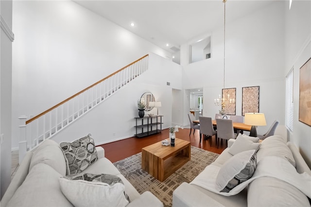 living room with a towering ceiling, hardwood / wood-style floors, and a notable chandelier