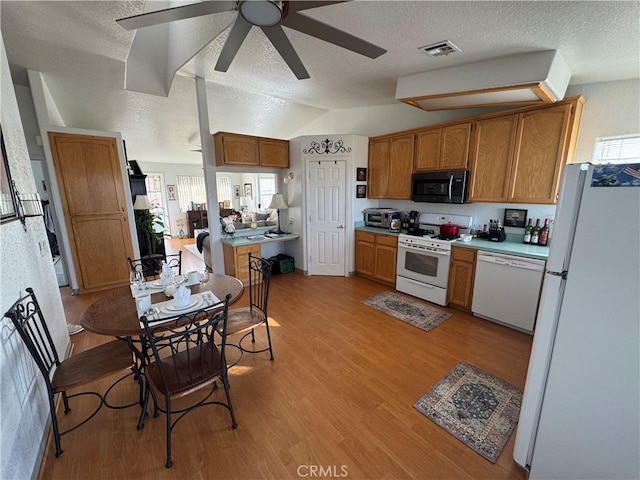 kitchen with lofted ceiling, a textured ceiling, light wood-type flooring, a wealth of natural light, and white appliances