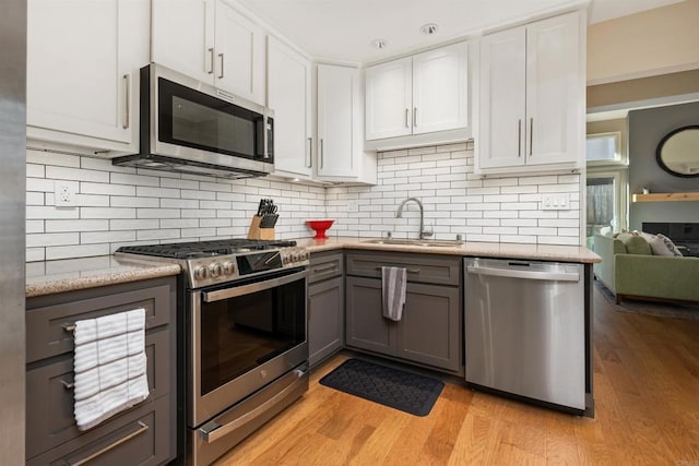 kitchen with appliances with stainless steel finishes, white cabinetry, sink, gray cabinetry, and backsplash