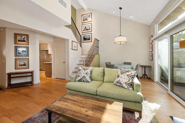 living room featuring light hardwood / wood-style flooring and vaulted ceiling with beams