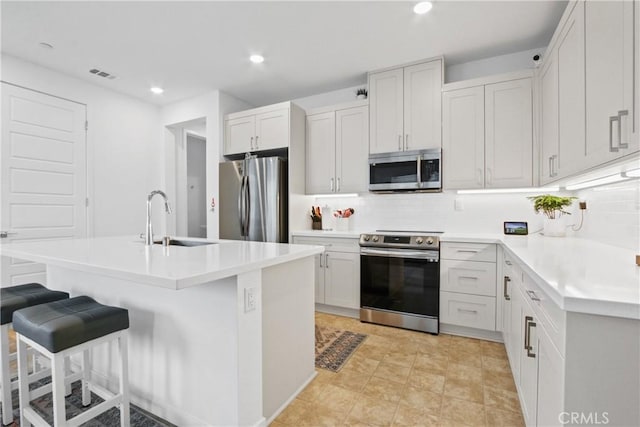 kitchen featuring appliances with stainless steel finishes, a kitchen breakfast bar, sink, and white cabinets