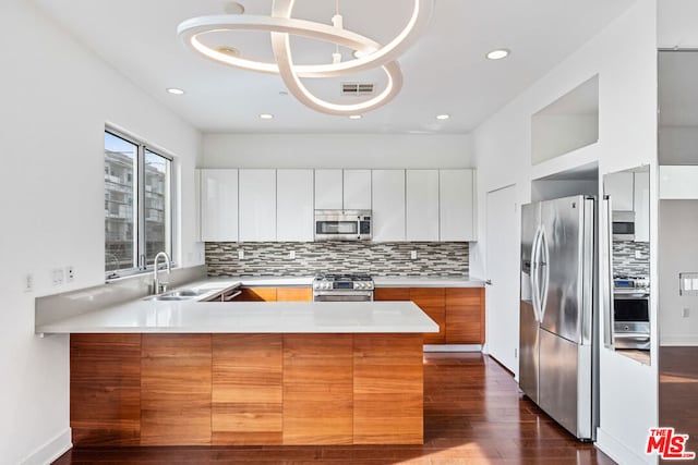 kitchen with sink, white cabinets, hanging light fixtures, kitchen peninsula, and stainless steel appliances