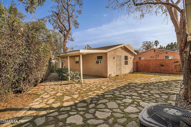 rear view of house with central AC unit and a patio