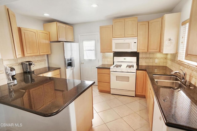 kitchen featuring light brown cabinets, sink, dark stone countertops, and white appliances