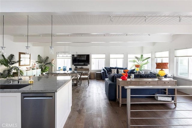 kitchen featuring beamed ceiling, sink, dark stone countertops, white cabinets, and stainless steel dishwasher