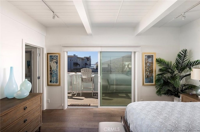 bedroom with dark hardwood / wood-style floors, track lighting, access to exterior, and beamed ceiling