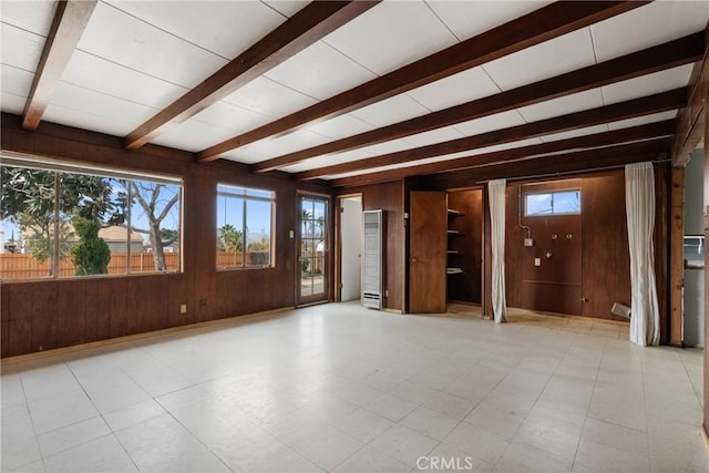 spare room with beam ceiling and wooden walls