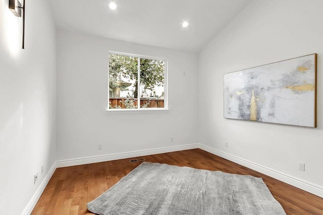 unfurnished room featuring wood-type flooring and vaulted ceiling