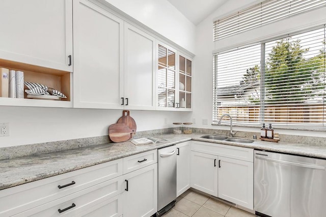 kitchen featuring sink, light stone counters, light tile patterned floors, stainless steel dishwasher, and white cabinets