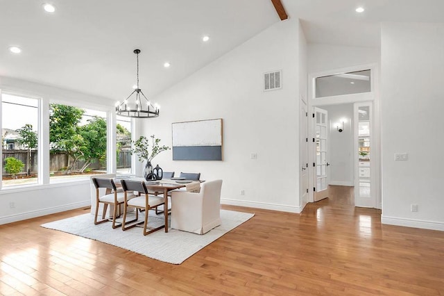 dining room featuring high vaulted ceiling, a chandelier, and light hardwood / wood-style floors