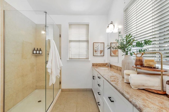 bathroom featuring tiled shower, vanity, and tile patterned flooring