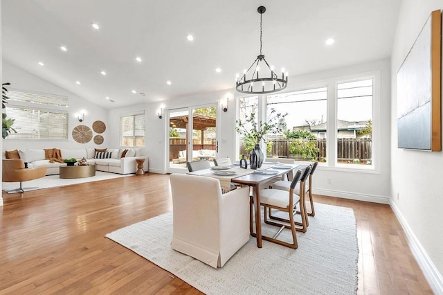 dining area with lofted ceiling, light hardwood / wood-style floors, and a chandelier