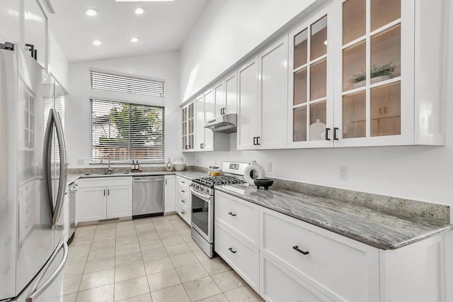 kitchen featuring sink, light tile patterned floors, appliances with stainless steel finishes, white cabinetry, and light stone countertops