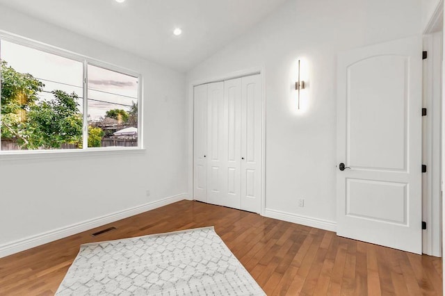 bedroom with wood-type flooring, vaulted ceiling, and a closet