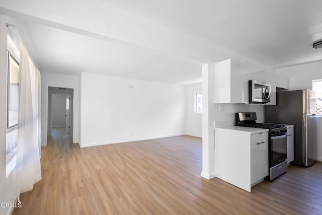 kitchen with light wood-type flooring, white cabinets, and appliances with stainless steel finishes