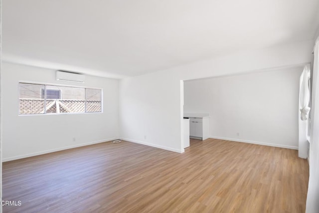 empty room featuring a wall unit AC and light hardwood / wood-style flooring