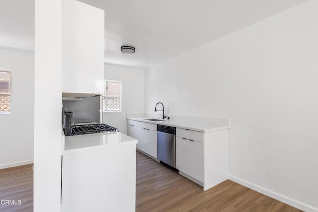 kitchen featuring sink, white cabinetry, stove, stainless steel dishwasher, and light wood-type flooring