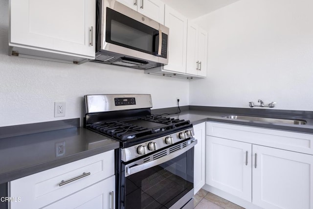 kitchen with white cabinetry, appliances with stainless steel finishes, light tile patterned flooring, and sink