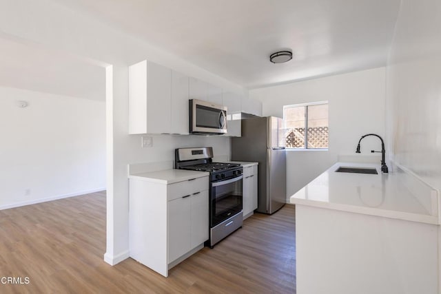 kitchen featuring white cabinetry, appliances with stainless steel finishes, sink, and light wood-type flooring