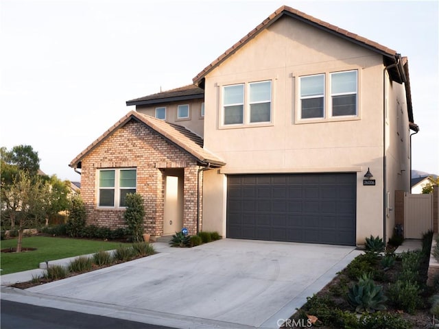 view of front of home featuring brick siding, a garage, driveway, and stucco siding