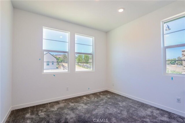 unfurnished room with dark colored carpet