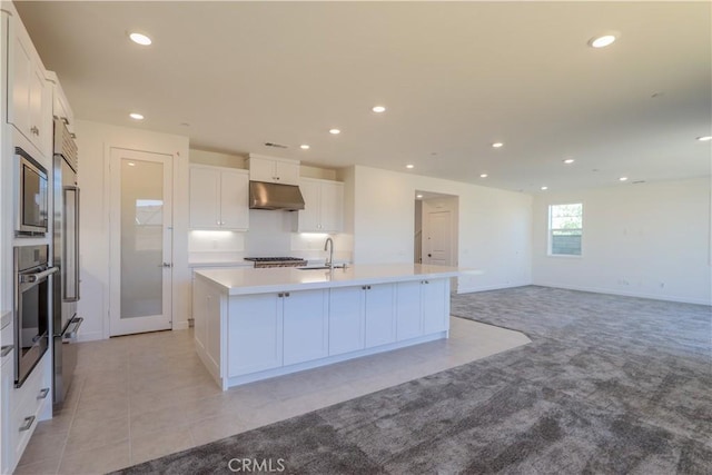 kitchen with stainless steel appliances, sink, a center island with sink, and white cabinets