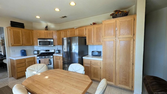 kitchen featuring tasteful backsplash, light tile patterned floors, and stainless steel appliances