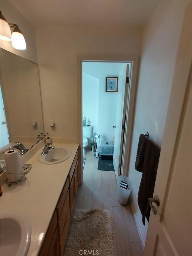 bathroom with hardwood / wood-style flooring, vanity, and toilet