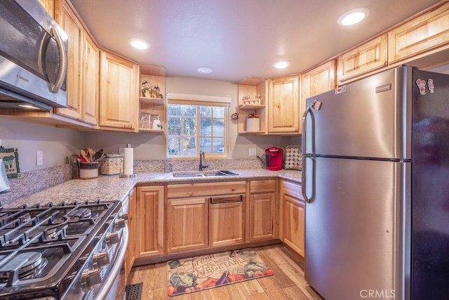 kitchen with stainless steel appliances, sink, light brown cabinets, and light hardwood / wood-style flooring