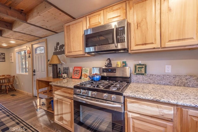 kitchen with light stone counters, hardwood / wood-style floors, light brown cabinets, and appliances with stainless steel finishes