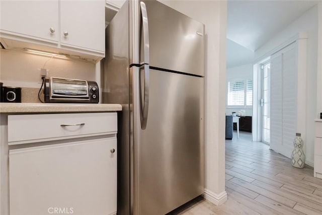 kitchen with white cabinetry, stainless steel fridge, and light hardwood / wood-style flooring