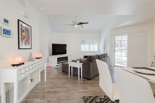 living room featuring lofted ceiling, light hardwood / wood-style floors, and ceiling fan