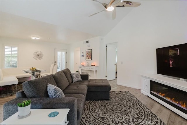 living room featuring ceiling fan, high vaulted ceiling, and light hardwood / wood-style floors