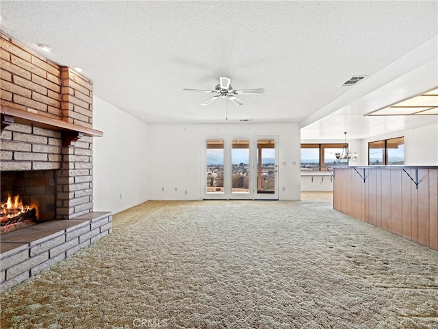 unfurnished living room featuring light carpet, a brick fireplace, a textured ceiling, and ceiling fan