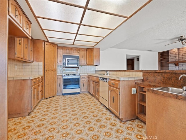 kitchen featuring appliances with stainless steel finishes, sink, a textured ceiling, and kitchen peninsula