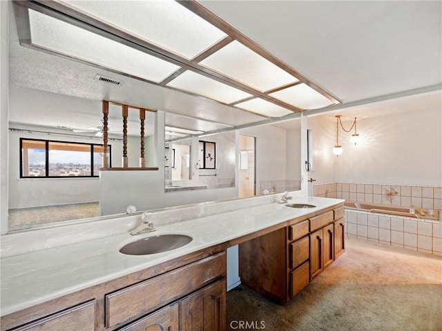 bathroom with tiled tub and vanity