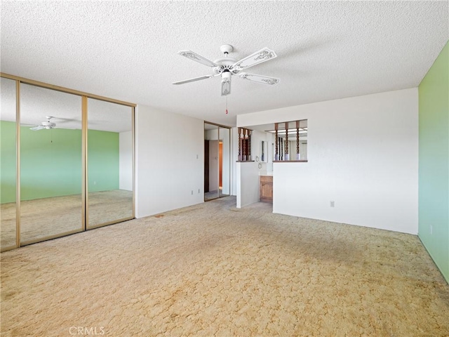 unfurnished room featuring a textured ceiling, ceiling fan, and carpet flooring