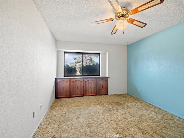 unfurnished room with ceiling fan, light carpet, and a textured ceiling