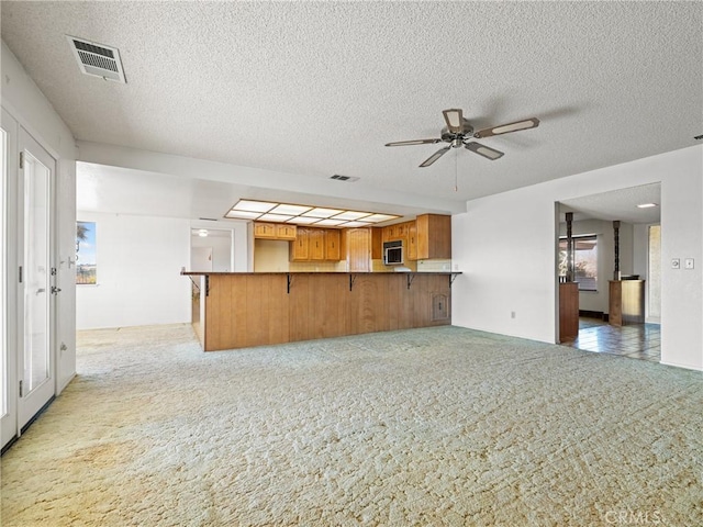 kitchen with light carpet, a textured ceiling, kitchen peninsula, and ceiling fan