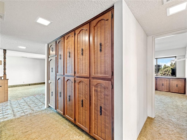 hallway with light carpet and a textured ceiling