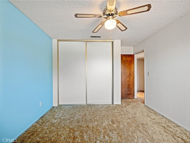 unfurnished bedroom featuring ceiling fan, light carpet, a textured ceiling, and a closet