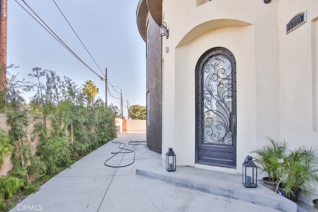 property entrance with fence and stucco siding