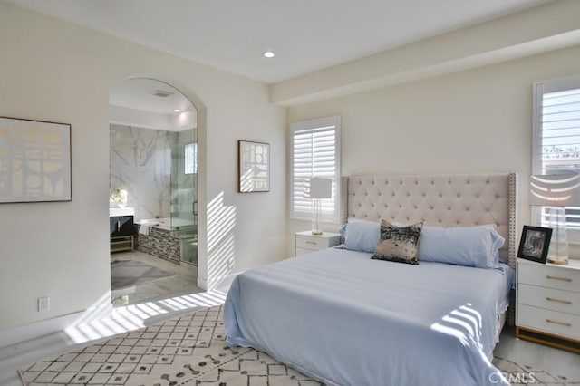 bedroom with arched walkways, ensuite bathroom, and recessed lighting