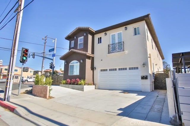 view of front of property with stucco siding, concrete driveway, a gate, fence, and a garage