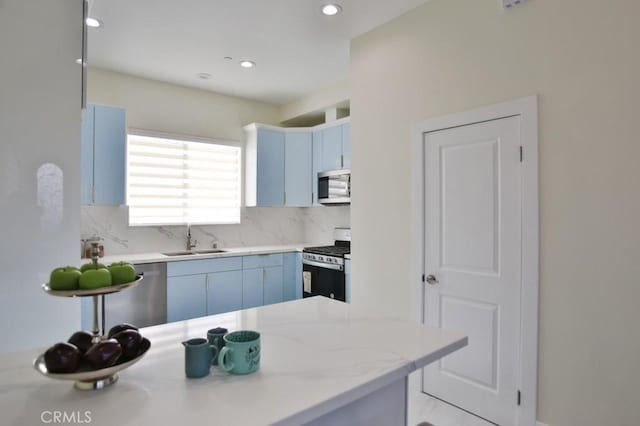 kitchen with stainless steel appliances, sink, blue cabinetry, and kitchen peninsula