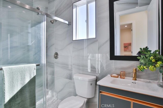 bathroom with walk in shower, vanity, toilet, and tile walls